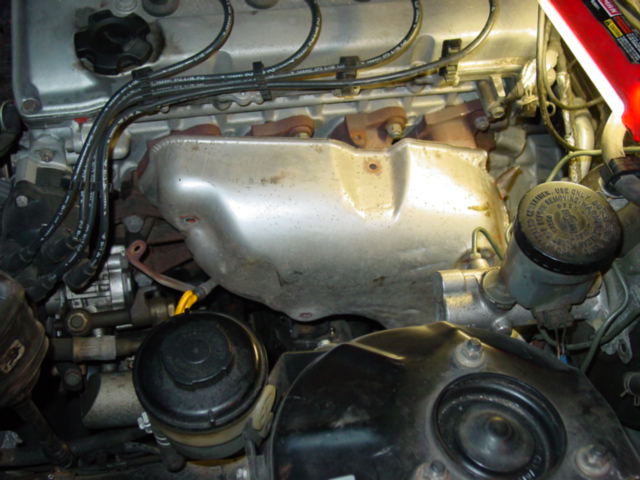 Remove the stock heat shield. There are several bolts along the top and near the primary catalytic converter. Getting this cover off will be tricky just be patient and avoid breaking anything.