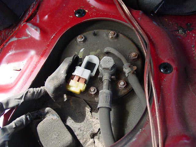 Remove the dust shield from the electrical connector and disconnect the harness.