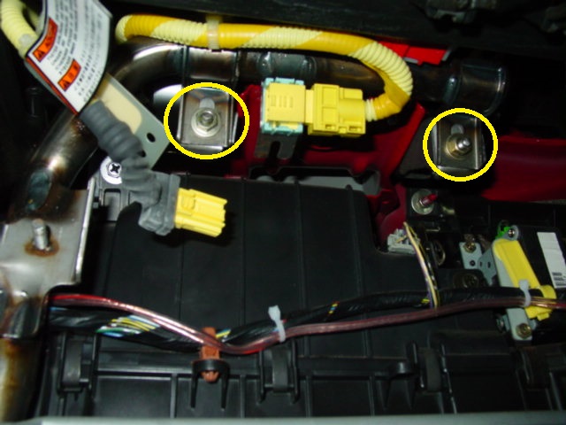 With the cover out of the way, disconnect the yellow air bag harness plug. Also, remove the two nuts located on either side of the yellow plug.
