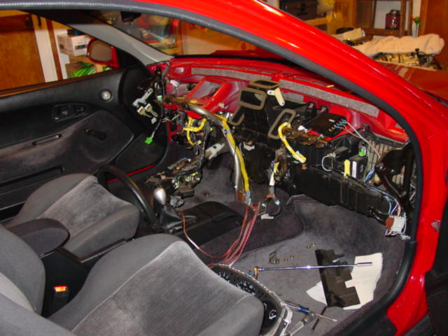 At this point, the dash can come out.  The dashboard harness plugs into the chassis harness just above the fuse panel.  As you pull it away, take care to disconnect the ground wire that attaches to a metal tab behind the cluster. Watch or any other connectors you have missed.